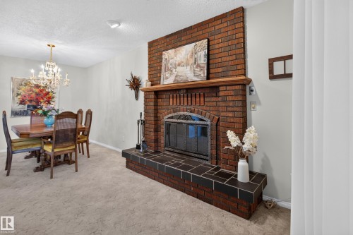 Brick fireplace featuring a wood mantel and tile hearth - 17603 85 Avenue Nw, Edmonton, AB 