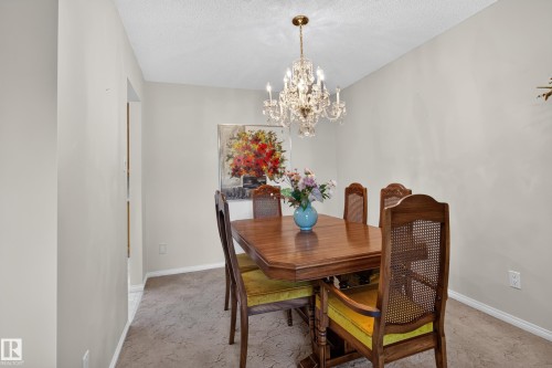 Dining area featuring neutral wall tones, a textured ceiling, and a crystal chandelier - 17603 85 Avenue Nw, Edmonton, AB 