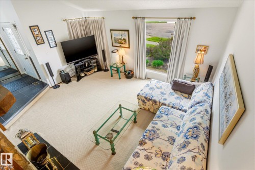 Carpeted living area featuring a large window with drapes, a tiled entryway, and a built-in fireplace with a black tile hearth - 59 Patterson Crescent, St. Albert, AB - Indoor
