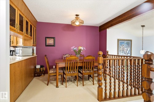 Dining area featuring a wood-finish dining table, ceiling-mounted light fixture, and wood-finish cabinetry with glass panel inserts and a light-toned countertop - 59 Patterson Crescent, St. Albert, AB - Indoor Photo Showing Dining Room