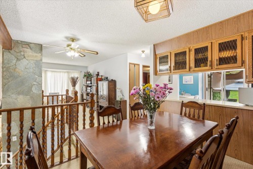 Dining area featuring a wood-finish table, wood-finish cabinetry with glass inserts, and an overhead light fixture - 59 Patterson Crescent, St. Albert, AB - Indoor Photo Showing Dining Room