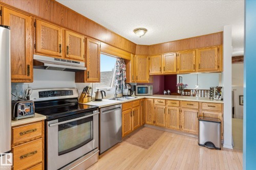 Kitchen featuring wood cabinetry, light countertops, stainless steel appliances, and wood-finish flooring - 59 Patterson Crescent, St. Albert, AB - Indoor Photo Showing Kitchen