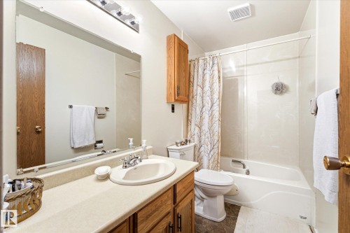 Bathroom featuring a single vanity with an integrated sink, broad wall mirror, and overhead vanity lighting - 59 Patterson Crescent, St. Albert, AB - Indoor Photo Showing Bathroom
