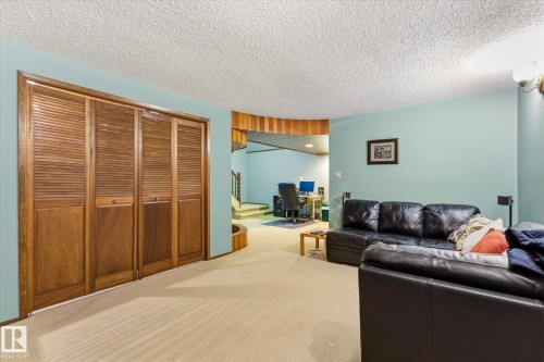 Louvered bifold doors featuring a wood finish, light blue wall paint, and textured ceiling - 59 Patterson Crescent, St. Albert, AB - Indoor Photo Showing Living Room
