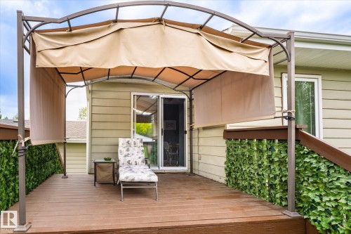 Spacious outdoor deck featuring wood-finish flooring, a metal-framed gazebo with a retractable fabric canopy, and a sliding glass door for interior access - 59 Patterson Crescent, St. Albert, AB - Outdoor With Exterior
