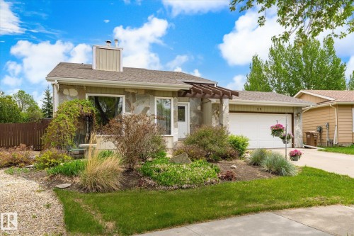 Stone-clad exterior featuring a two-car garage, mature landscaping, a pergola over the entrance, and a well-maintained roofline - 59 Patterson Crescent, St. Albert, AB - Outdoor