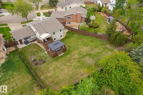 Expansive backyard featuring a fenced perimeter, a raised wood deck with an awning, a separate wood gazebo structure, and a concrete patio area - 59 Patterson Crescent, St. Albert, AB - Outdoor