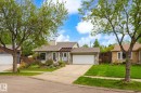 Exterior featuring a stone facade, white entry door, integrated garage, concrete driveway, and mature front landscaping - 59 Patterson Crescent, St. Albert, AB  - Outdoor With Facade 