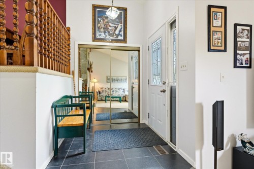 Entryway featuring dark tile flooring, a white paneled door with decorative glass inserts, and a mirrored closet door - 59 Patterson Crescent, St. Albert, AB - Indoor Photo Showing Other Room