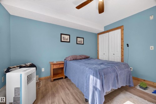 Room featuring wood-finish flooring, a ceiling fan with integrated lighting, and a closet with bifold doors framed by natural wood trim - 414 11214 80 Street, Edmonton, AB 