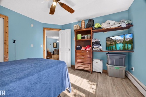 Bedroom featuring light blue walls, wood-finish flooring, and a ceiling fan with light fixture - 414 11214 80 Street, Edmonton, AB 