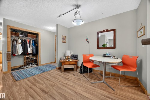 Spacious interior featuring wood-finish flooring, a built-in closet with shelving and hanging space, light gray wall paint, and a textured white ceiling - 414 11214 80 Street, Edmonton, AB 