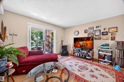 Living area with wood-finish flooring, light-toned walls, and a white textured ceiling - 