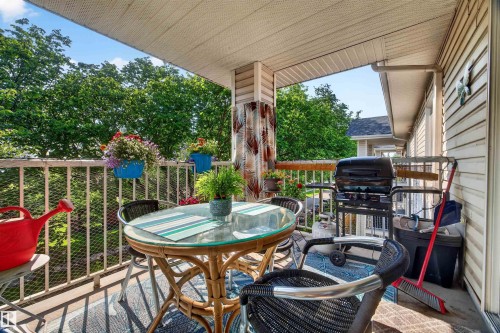 Covered balcony featuring a white railing, beige siding, and ample space for outdoor furnishings - 414 11214 80 Street, Edmonton, AB 