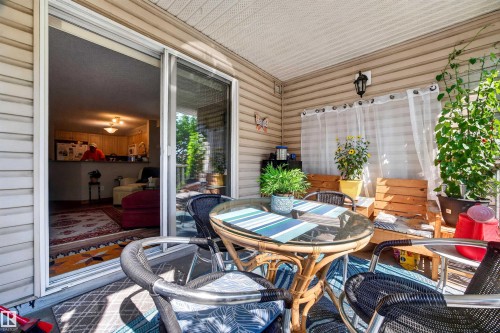 Outdoor patio featuring a glass sliding door, vinyl siding, and an overhead lighting fixture - 414 11214 80 Street, Edmonton, AB 