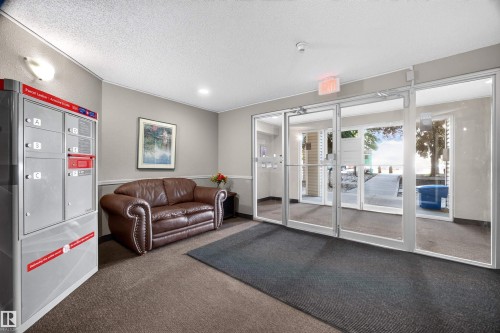 Building entrance featuring glass double doors, light gray wall paint, textured ceiling, and recessed lighting - 414 11214 80 Street, Edmonton, AB 