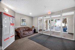 Building entrance featuring glass double doors, light gray wall paint, textured ceiling, and recessed lighting - 