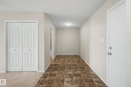Entryway featuring a white paneled door, patterned floor tiles, and neutral wall paint - 404 1080 Mcconachie Boulevard, Edmonton, AB 