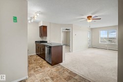 Open-concept living space with a kitchen island featuring a double-basin sink, stainless steel dishwasher, and dark cabinetry - 