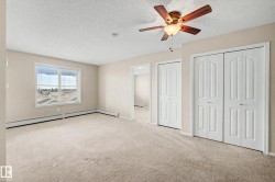 Spacious room featuring neutral carpet flooring, a window offering exterior views, two bi-fold panel doors, and a ceiling fan with integrated lighting - 