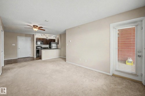 Open-concept living space with carpeted flooring, a ceiling fan, and a door to exterior - 404 1080 Mcconachie Boulevard, Edmonton, AB 