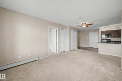 Carpeted living area featuring a ceiling fan, baseboard heating, and direct access to the kitchen space - 