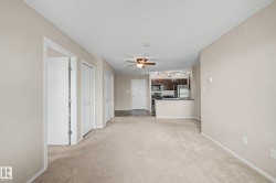 Open concept living area featuring neutral carpeting and a ceiling fan - 