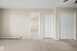 Carpeted interior space featuring neutral wall paint, a white baseboard heater, and multiple white bi-fold doors - 