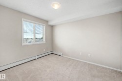 Carpeted room featuring a large window with blinds, neutral wall paint, and baseboard heating - 