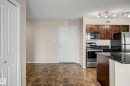Kitchen featuring stainless steel appliances, dark wood cabinetry, and a black countertop - 404 1080 Mcconachie Boulevard, Edmonton, AB 