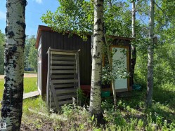 Compact outbuilding featuring dark wood-paneled siding and a white door with a wood-trimmed frame - 