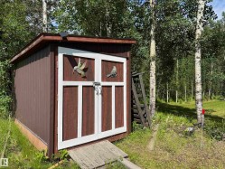 Storage shed featuring vertical brown siding and white double doors - 