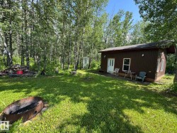 Wooded lot featuring a brown siding structure with white trim windows and a white entry door - 