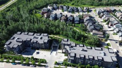 Contemporary multi-story residential buildings featuring balconies and a surrounding tree line - 