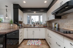 U-shaped kitchen featuring white cabinetry, dark countertops, a tile backsplash, recessed lighting, and a bay window - 