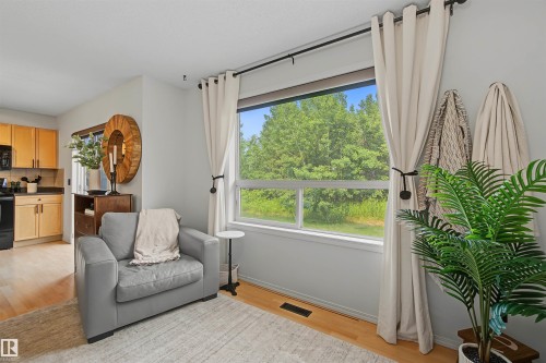 Expansive window overlooking lush greenery, featuring light wood-finish flooring - 15 450 Hyndman Crescent, Edmonton, AB 
