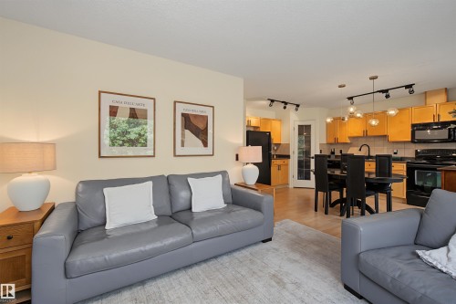 Open-concept living space featuring light-colored walls and wood-finish flooring - 15 450 Hyndman Crescent, Edmonton, AB 