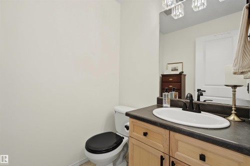 Powder room featuring a single vanity with wood cabinetry, matte black hardware, and an undermount sink - 15 450 Hyndman Crescent, Edmonton, AB 