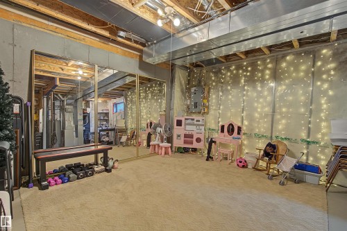 Unfinished basement featuring exposed concrete walls and ceiling joists, overhead utility ducting, and track lighting - 15 450 Hyndman Crescent, Edmonton, AB 