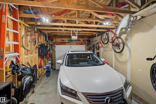 Attached two-car garage featuring exposed wood framing, concrete flooring, overhead lighting, and an automatic garage door - 15 450 Hyndman Crescent, Edmonton, AB 
