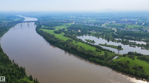 Expansive riverfront property featuring a winding waterway, lush green banks, and mature tree lines - 15 450 Hyndman Crescent, Edmonton, AB 