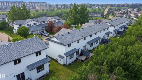 Row of modern townhomes featuring white siding and dark shingled roofs - 15 450 Hyndman Crescent, Edmonton, AB 