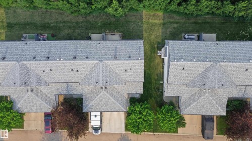 Aerial perspective of multiple properties featuring light gray shingle roofs, individual driveways, and private rear patios - 15 450 Hyndman Crescent, Edmonton, AB 