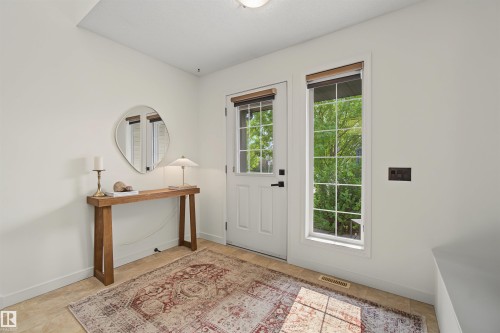 Entryway featuring a white paneled door with glass insert, grid-paned window, tile flooring, and light-toned walls - 15 450 Hyndman Crescent, Edmonton, AB 