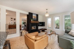 Living area featuring a black brick fireplace with a wood mantle, multiple windows, and light-toned flooring - 