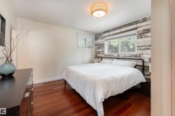 Interior room featuring rich wood-finish flooring, a textured accent wall, and two windows providing natural light - 