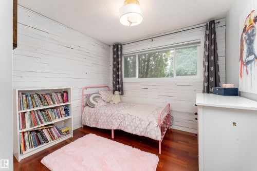 Bedroom featuring warm wood-finish flooring complements light-colored walls - 7816 142 Street, Edmonton, AB 