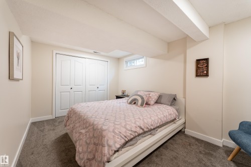 Carpeted room featuring a double bi-fold closet, a white baseboard trim, and a high horizontal window - 7816 142 Street, Edmonton, AB 