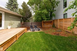 Expansive backyard featuring a natural wood deck, vibrant green lawn, and a light wood privacy fence - 