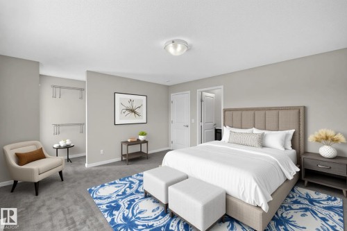 Carpeted sleeping area featuring neutral wall tones, a recessed closet opening with shelving, a ceiling-mounted light fixture, and white trim - 2460 15 Avenue, Edmonton, AB 